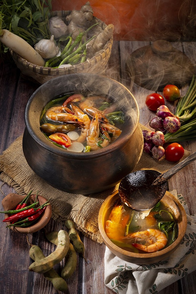 Dampfende Schale mit Sinigang-Garnelensuppe und Gemüse in einem Tontopf