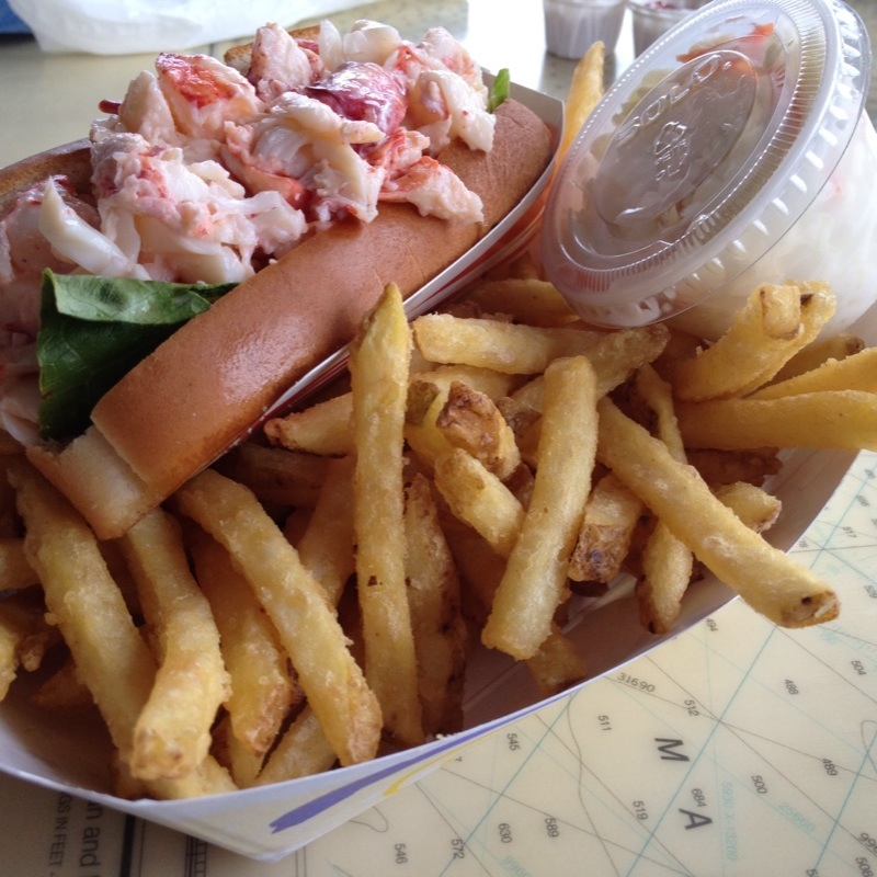 Lobster Roll mit Hummerfleisch im gerösteten Brötchen neben Pommes frites