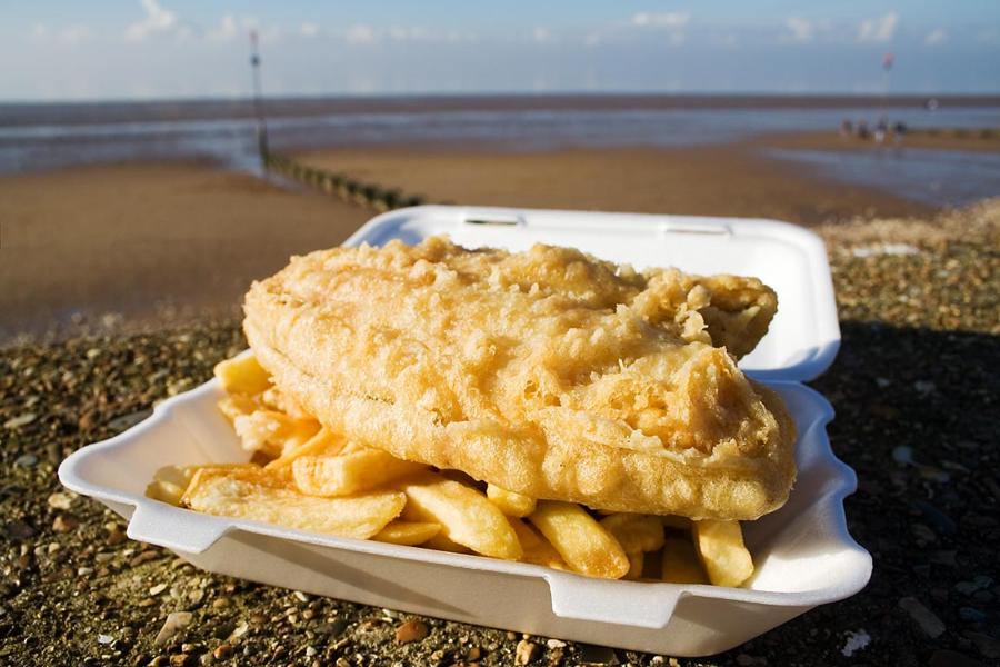 Portion Fish and Chips in einer Pappschale am Strand