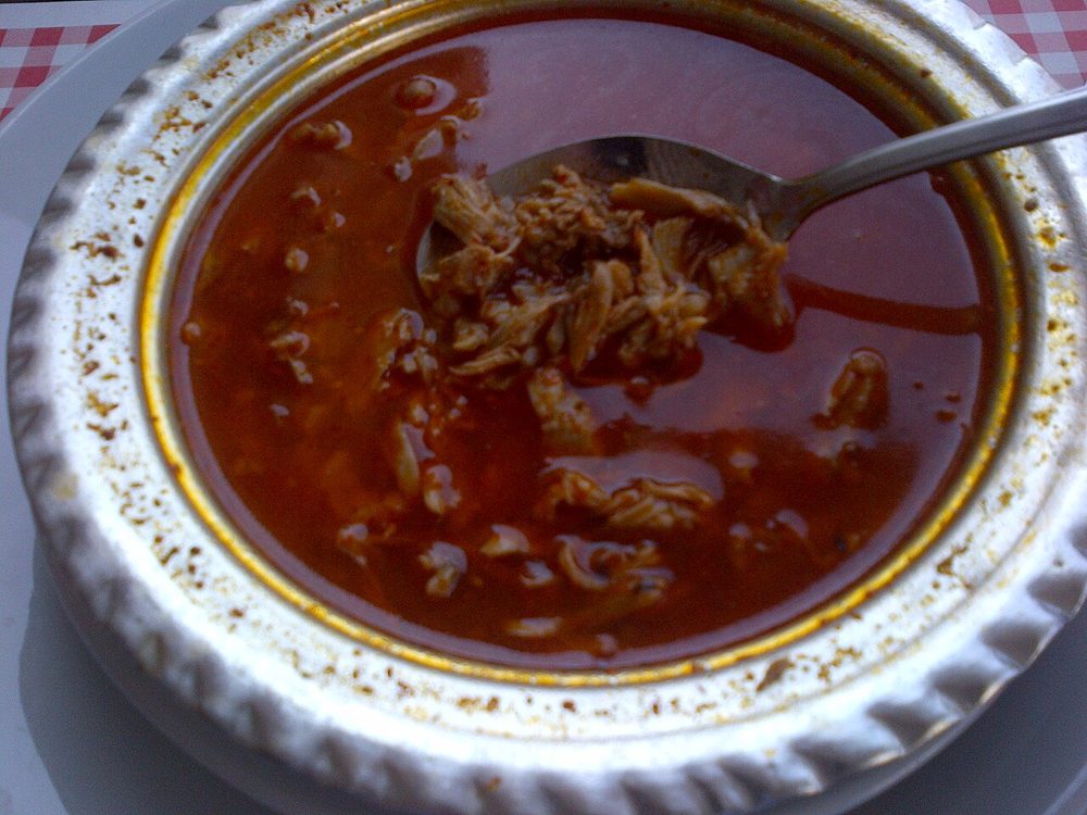 Schale Beyran-Suppe mit Lammfleisch in roter Bruehe, Loeffel darin