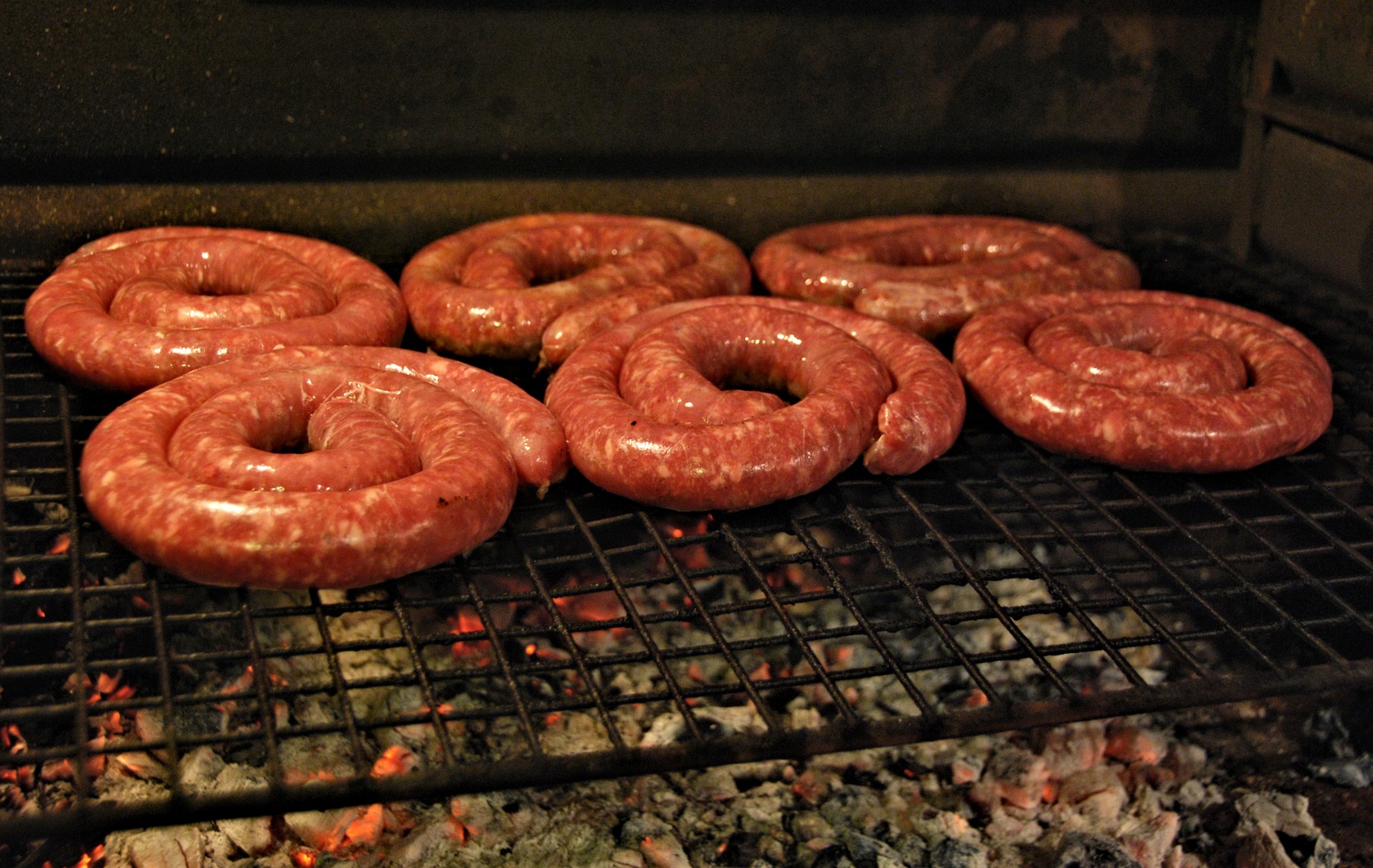 Spiralförmige Boerewors-Wurst auf einem Braai-Grill über Holzkohleglut