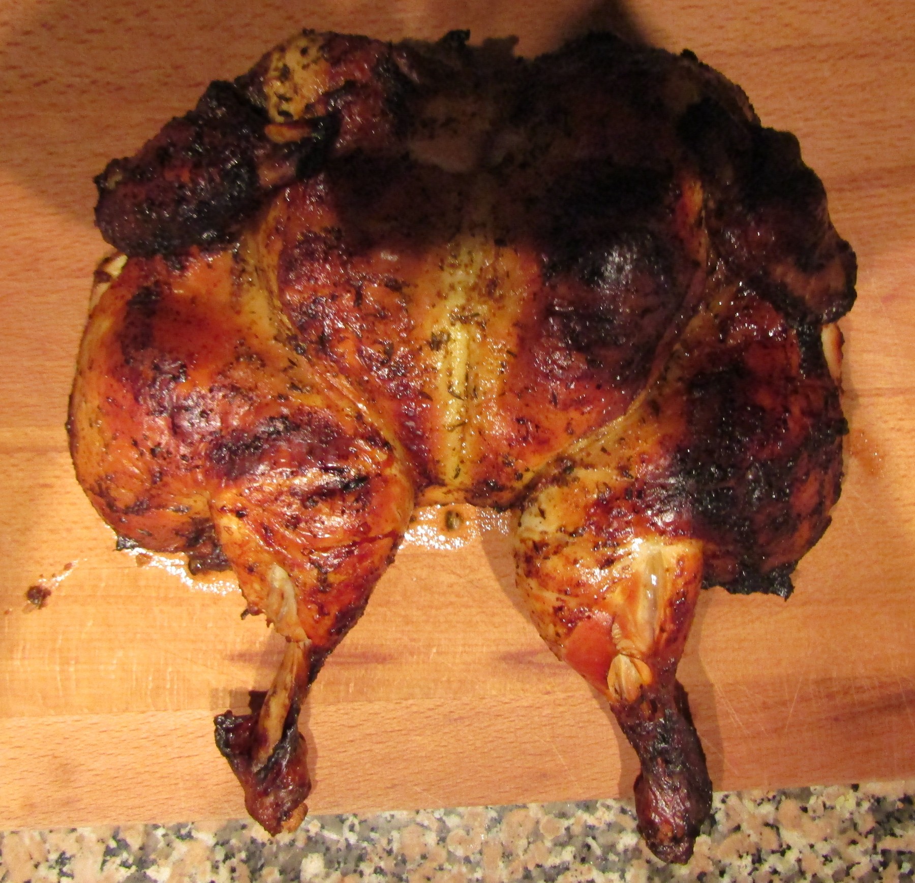 Gegrilltes Piri-Piri-Hähnchen mit dunkel gerösteter Haut, serviert mit Zitronenspalten