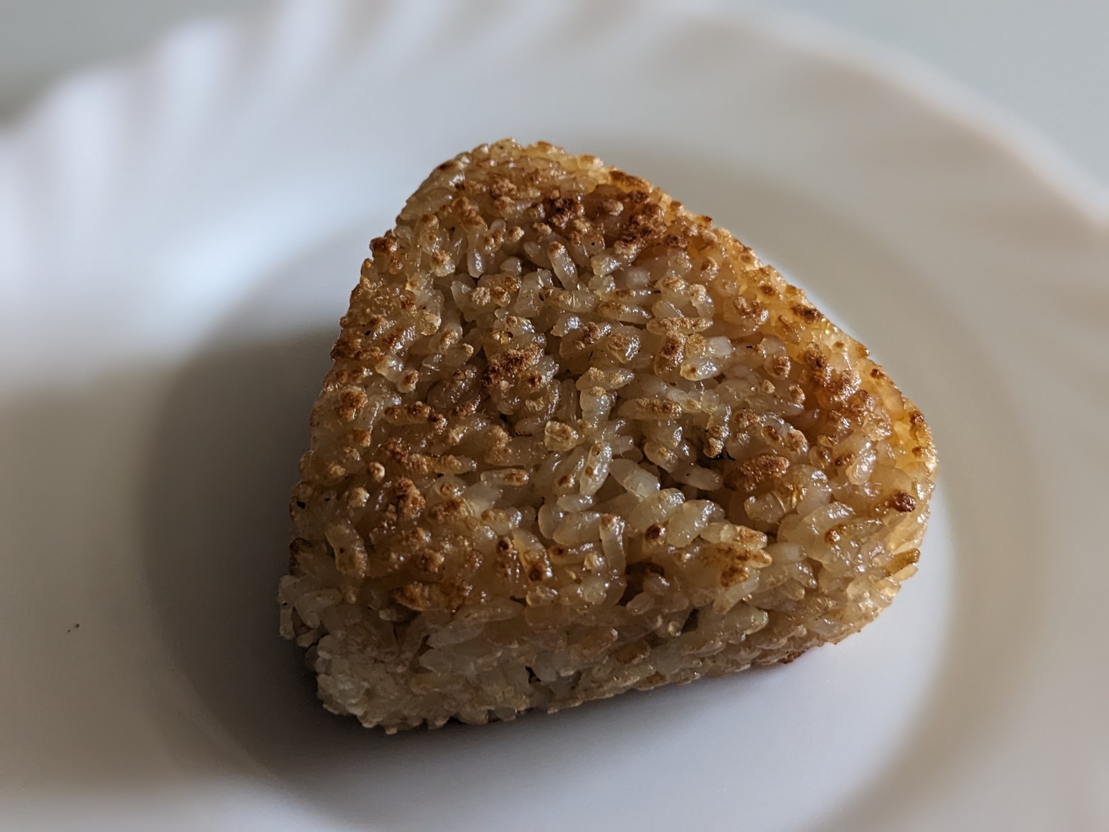 Knusprig gebräuntes dreieckiges Yaki Onigiri auf einem weißen Teller