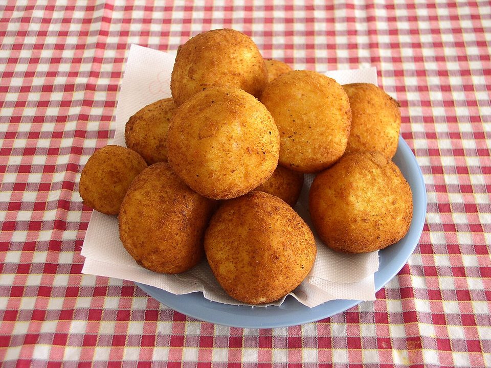 Goldbraun frittierte Arancini in einer Vitrine ausgelegt