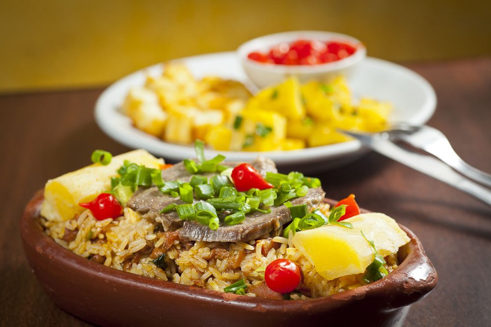 Tonschale mit Baião de dois, Käsewürfeln und Frühlingszwiebeln