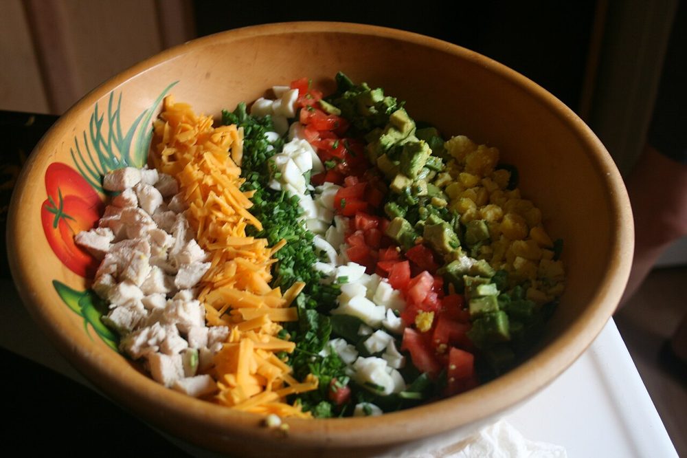Cobb Salad mit Reihen aus Ei, Bacon, Avocado und Käse in einer Schale