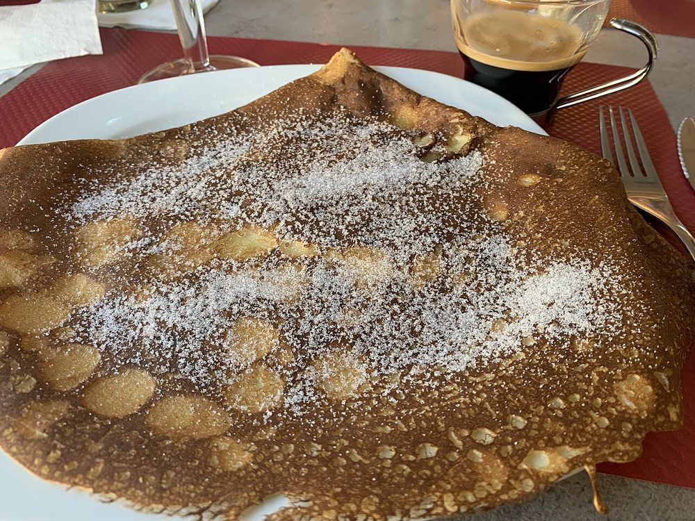 Große Crêpe mit Puderzucker auf einem Teller