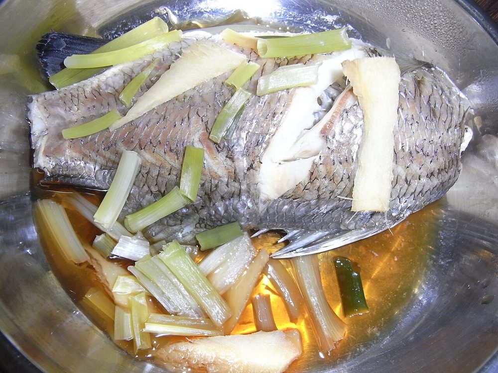 Ganzer gedämpfter Fisch mit Ingwer- und Frühlingszwiebelstreifen in Sojasoße
