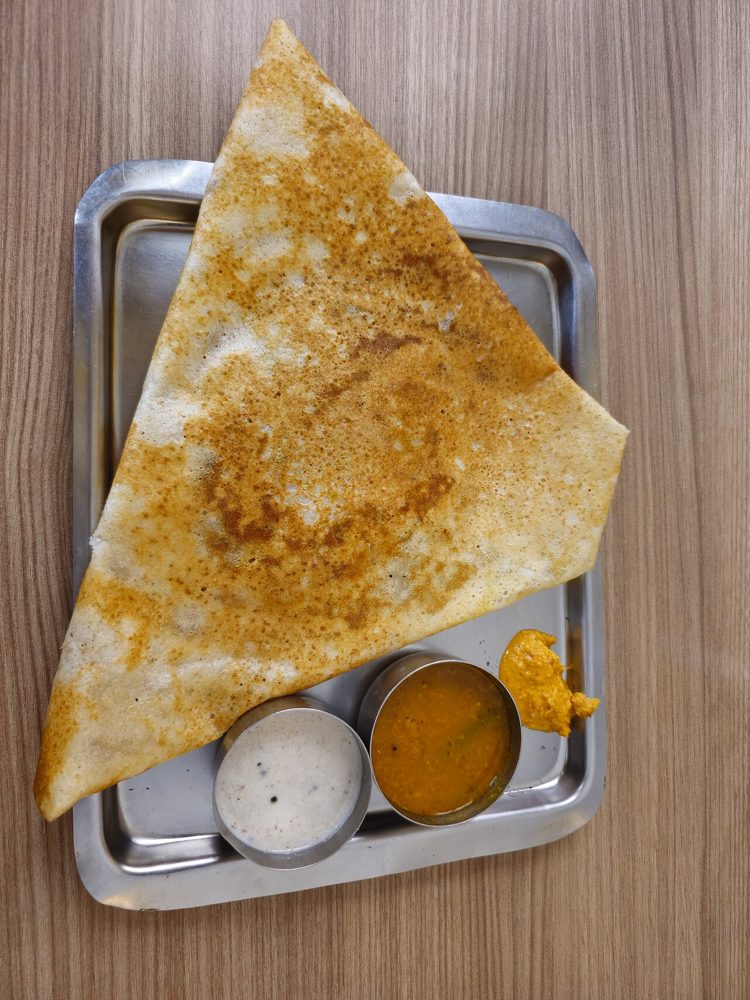 Gefaltete Masala Dosa mit Chutneys auf einem Metalltablett