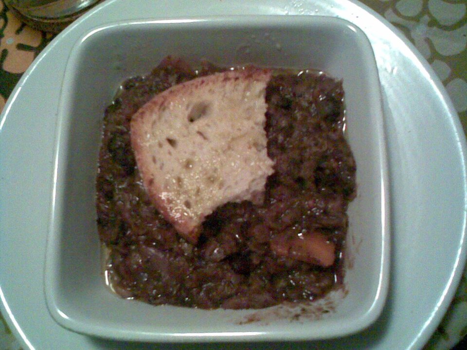 Schüssel Ribollita mit Brot, Kohl und Bohnen neben einem Stück Landbrot